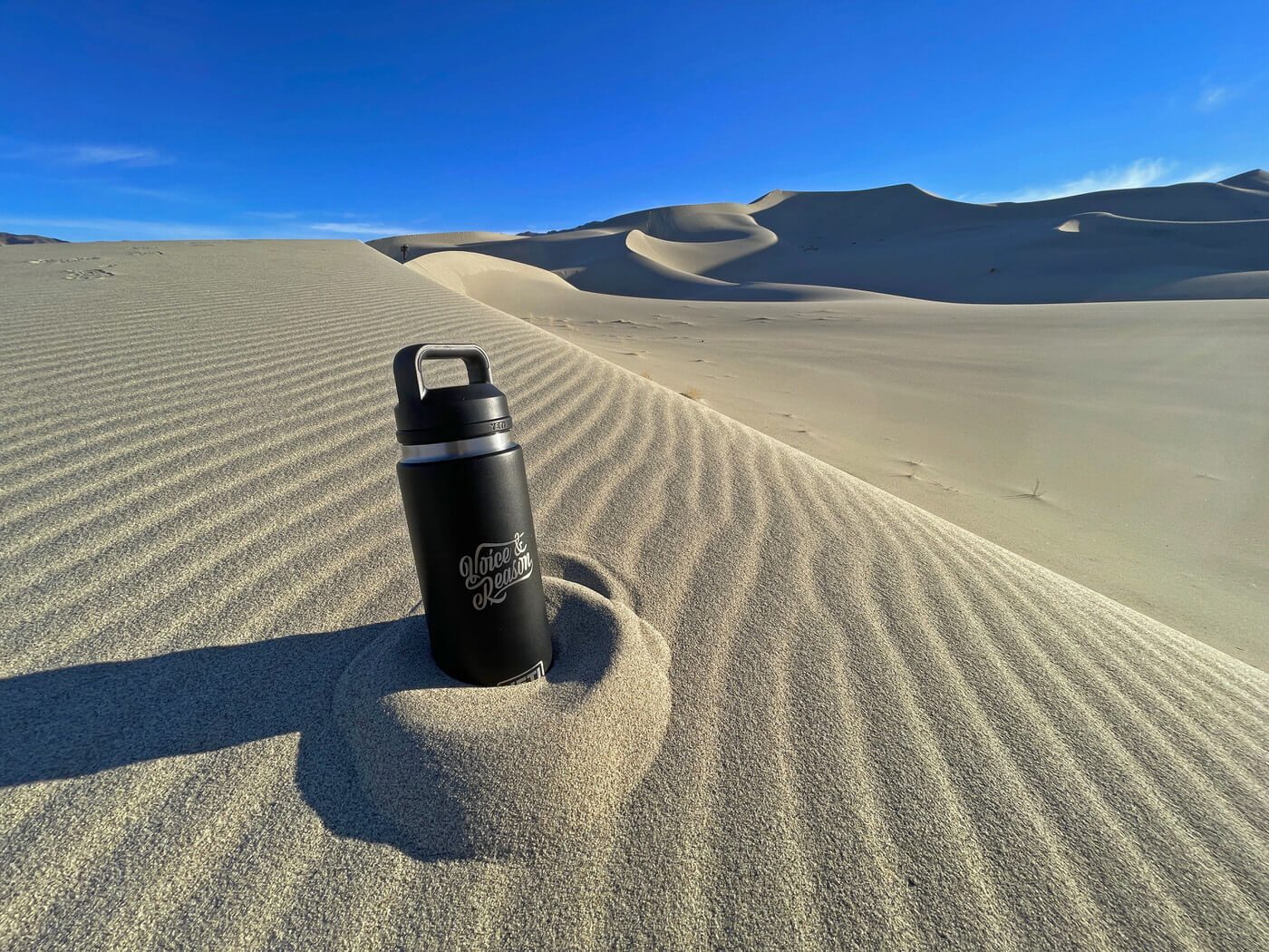Photo of Voice & Reason branded water container sitting in sand in the desert