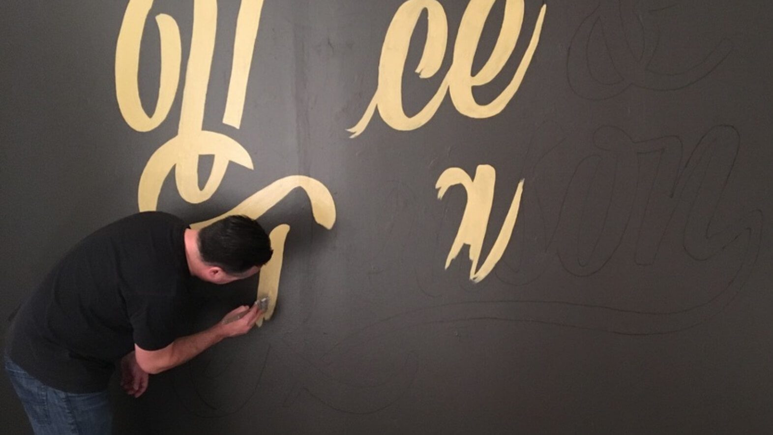 TJ Sugnet painting Voice & Reason logo on mural